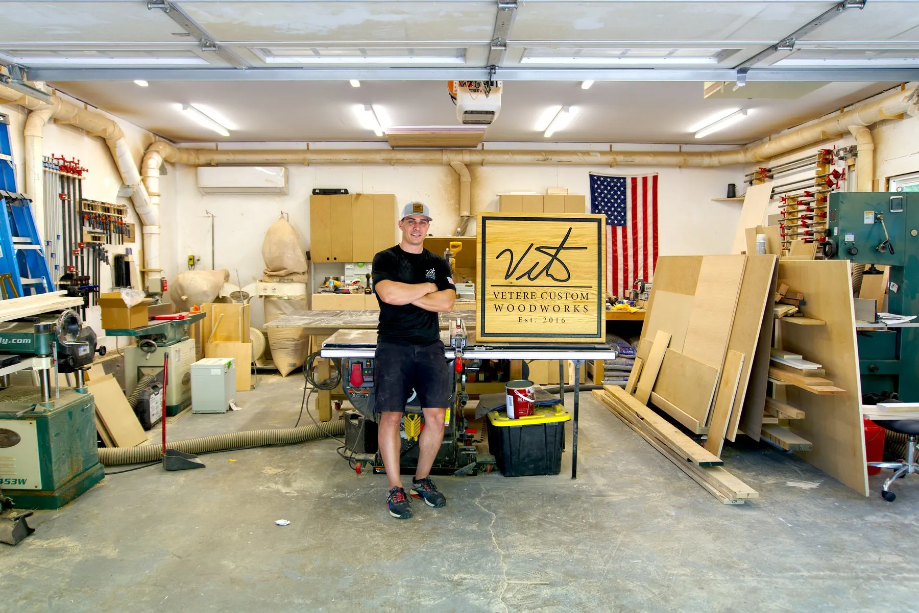 Woodworker beside a carved Vetere Custom Woodworks sign in his shop, brand photography by Coonan Creative